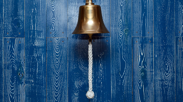 gold maritime bell hanging on a blue paneled wall