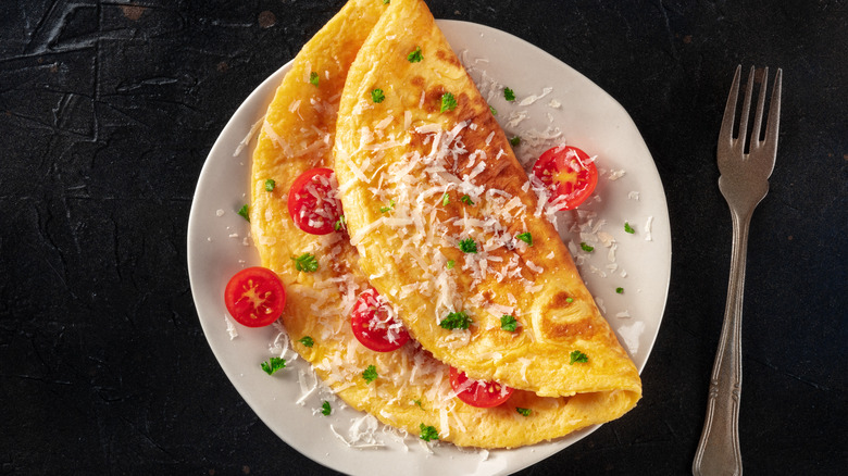 Omelette with cheese and tomatoes on black surface