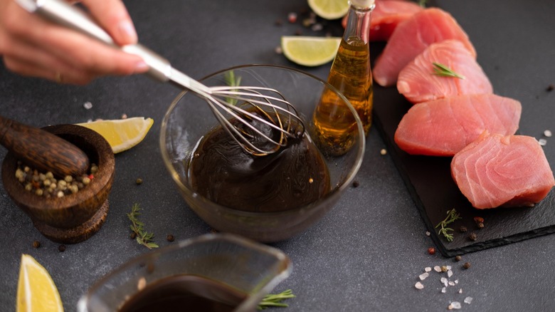 Person stirring marinade with various ingredients nearby
