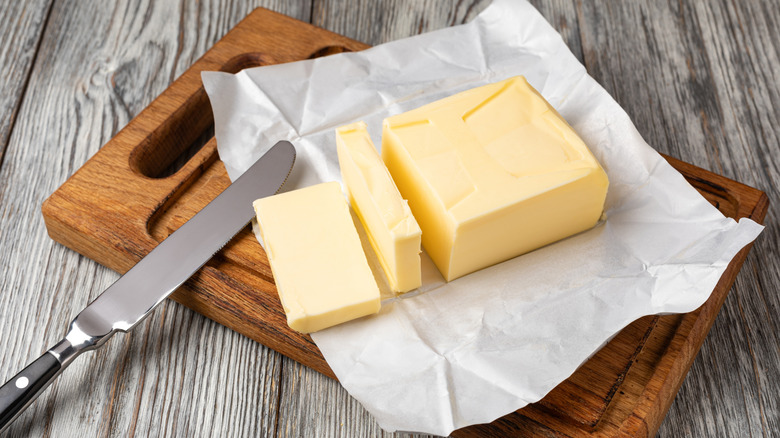 Sliced butter on a wooden cutting board with a butter knife