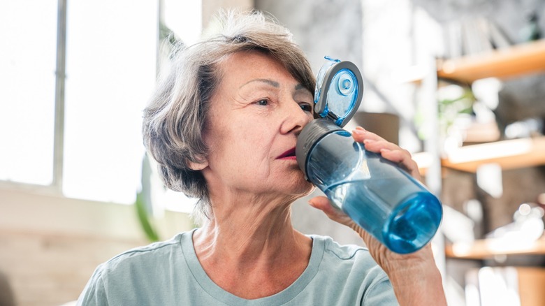 woman drinks liquid from water bottle