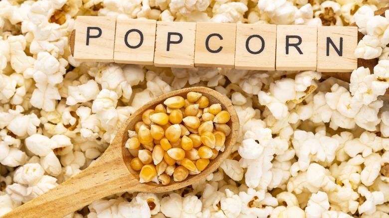 popcorn kernels on wooden spoon with letters