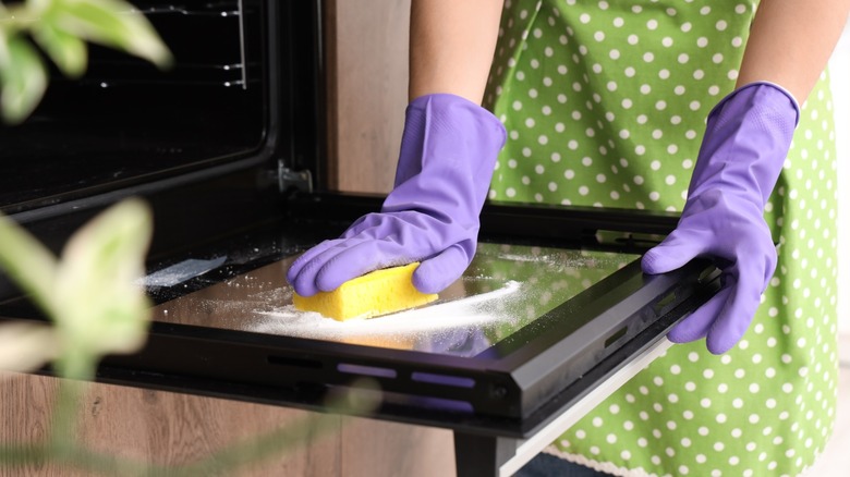 gloved hands scrub oven door