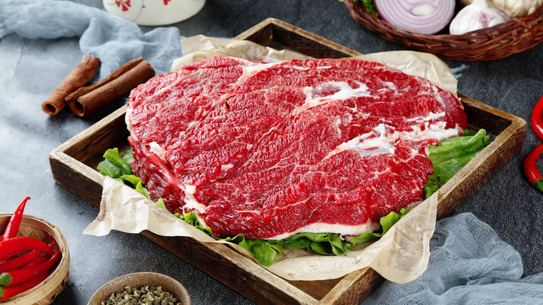 Fresh raw beef brisket cut displayed on wooden tray