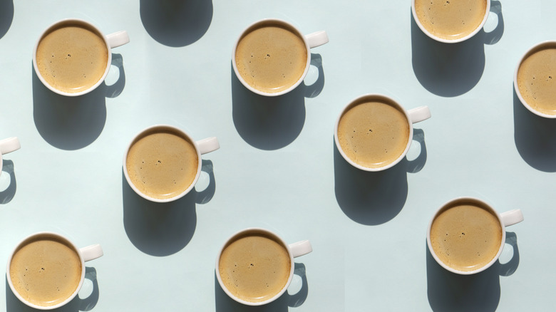repeating pattern of coffee cups, top-down view against a light blue background