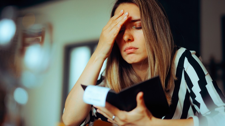 woman is upset with restaurant bill in folder