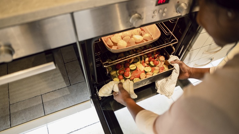 stacking two cooking pans in a crowded oven