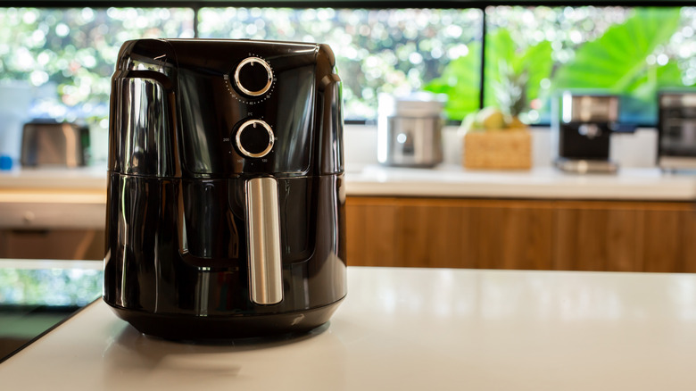 Black air fryer on white countertop.