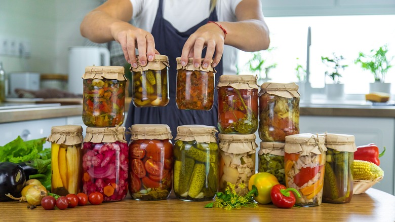 Person moving jars of canned food in kitchen.