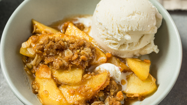 A bowl of apple cobbler topped with vanilla ice cream