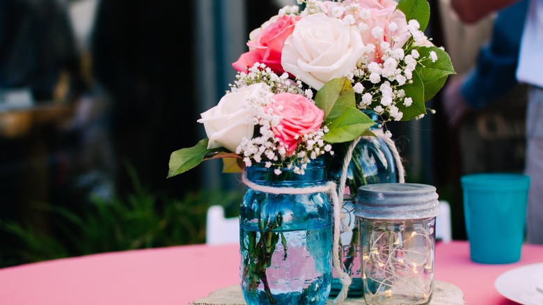 blue mason jar with roses and fairy lights