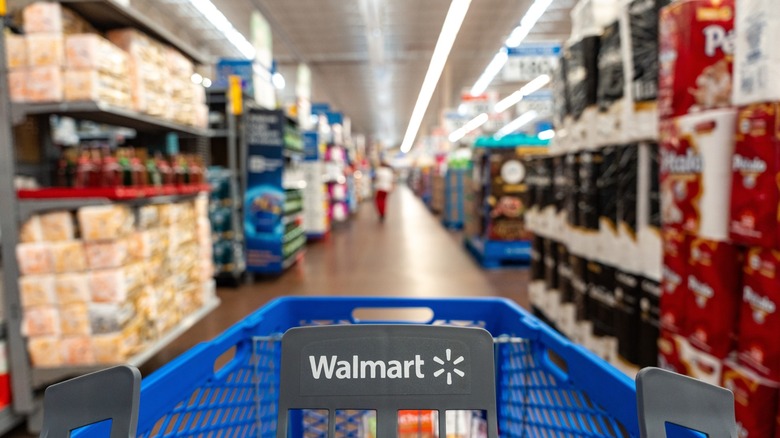 pushing a walmart shopping cart down store aisle