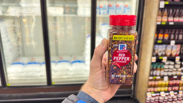 a hand holds a bottle of mccormick red pepper flakes