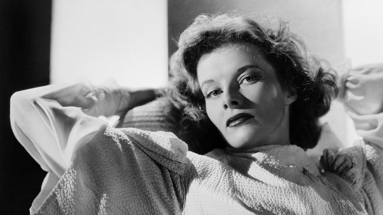 American actress Katharine Hepburn relaxes with her hands behind her head, black and white