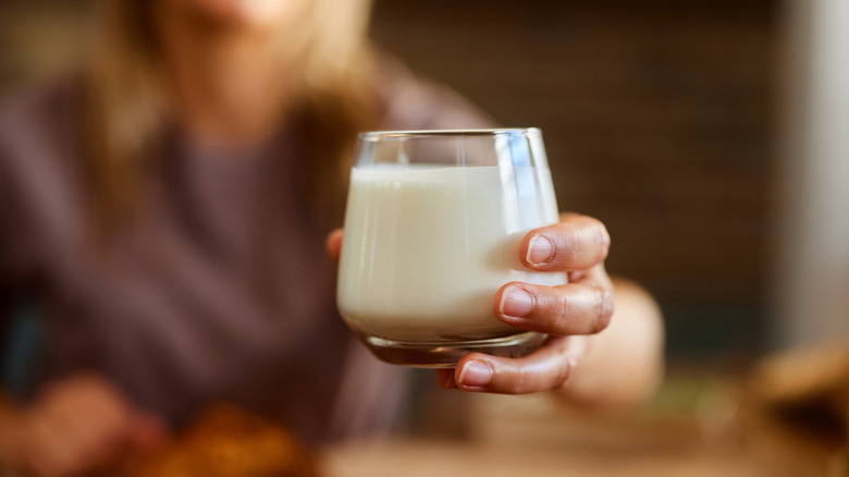 Someone holding out a glass of fresh milk