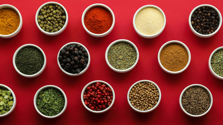 Assorted spices in bowls on a red background