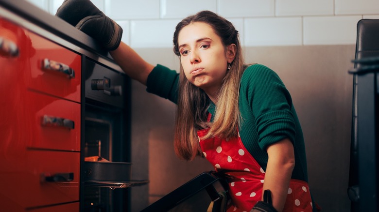 frustrated home cook hunches by oven