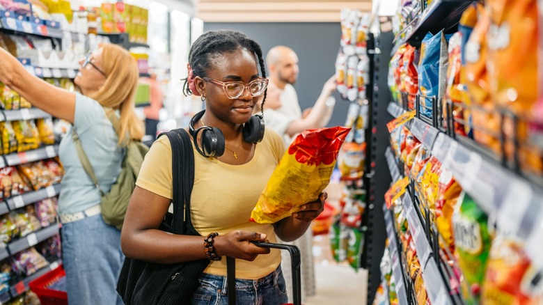 young woman shops for chips at grocery store