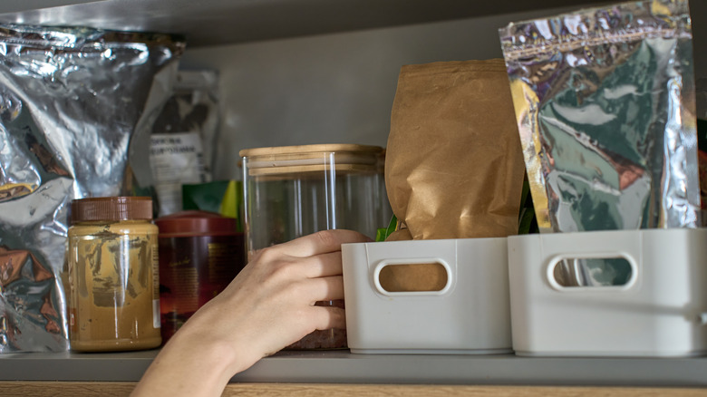 Closeup person's hand reaching into pantry
