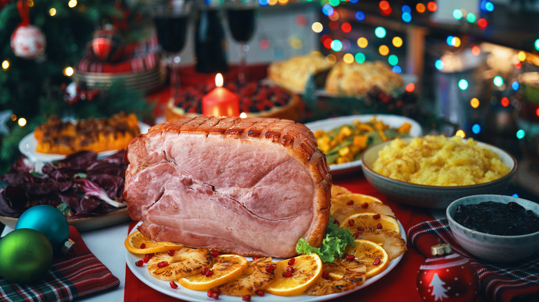 A close-up of a holiday ham surrounded by other holiday side dishes on a table