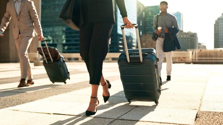 travelers walk with rolling luggage