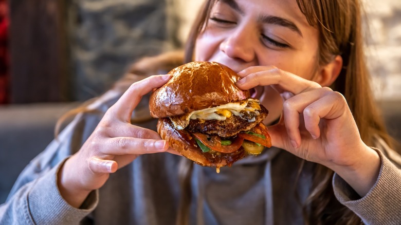 woman eats a large burger at a restaurant
