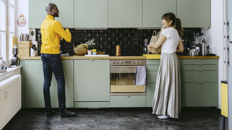 A kitchen features sage green slab cabinets