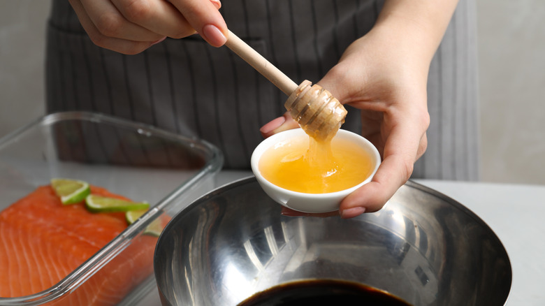 Closeup of hands adding honey into bowl with soy sauce