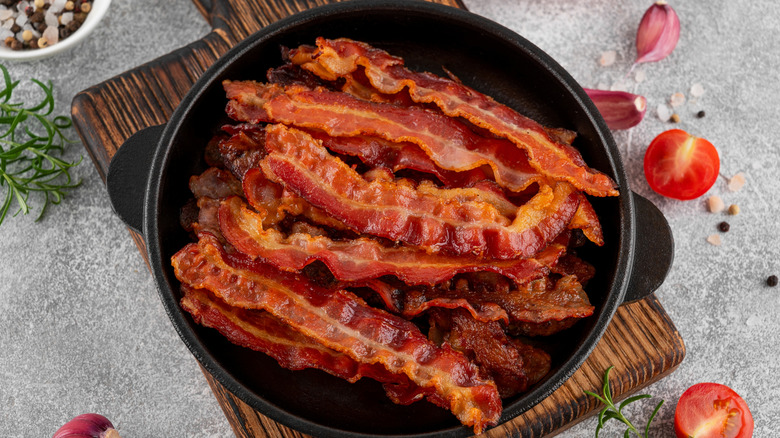 Fried slices of bacon for breakfast in a cast iron pan