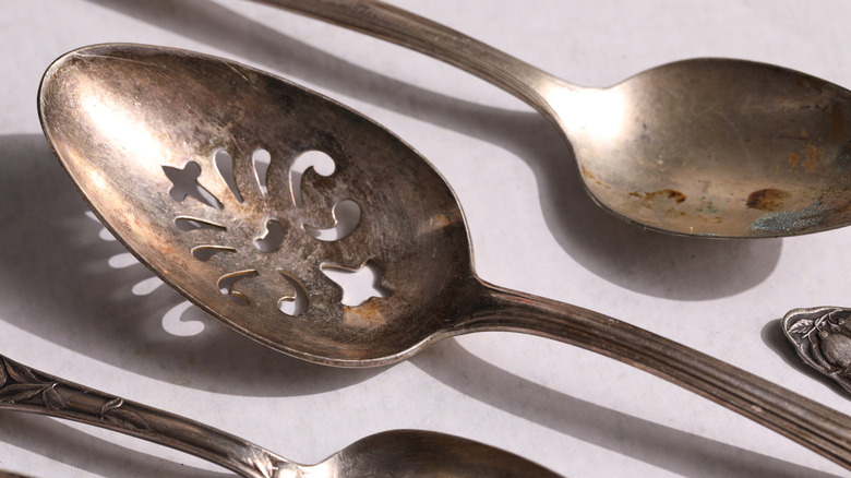 Closeup of tarnished silver spoons on white surface