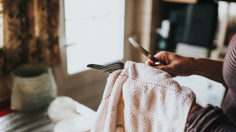Hand drying silverware with a cloth.
