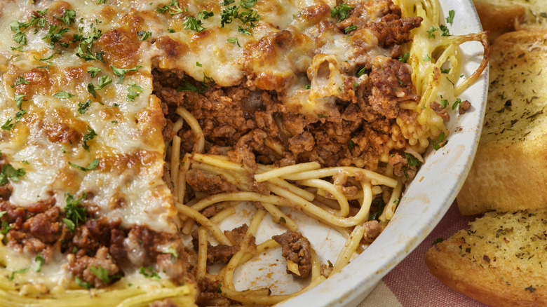 Baked spaghetti with meat sauce in round casserole dish