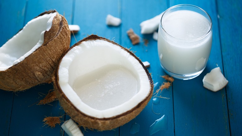 coconut milk in glass with split coconuts
