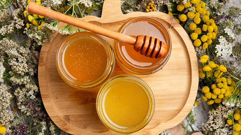Top-down view of three open jars of honey