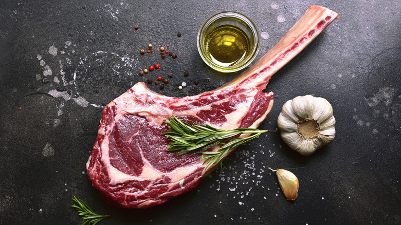 Raw tomahawk beef steak on a dark background