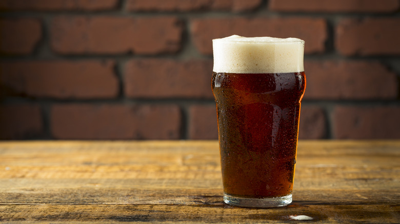 A pint of brown ale on a wooden table
