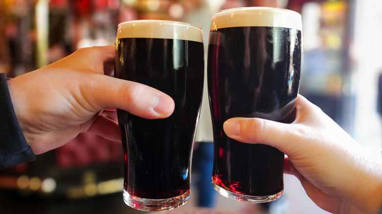 Two people clinking glasses of stout beer