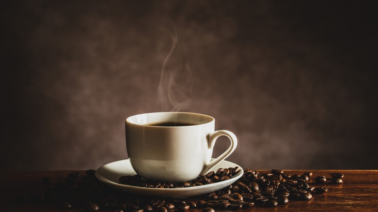 steaming mug of coffee with beans