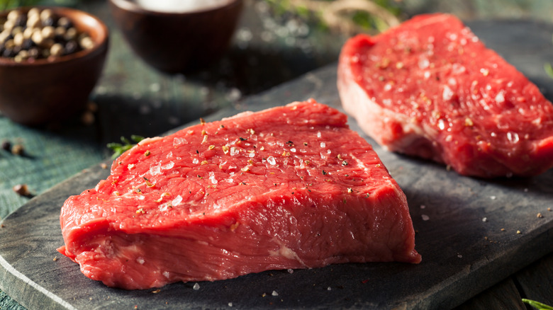 Close-up of raw, seasoned sirloin steak on a black board
