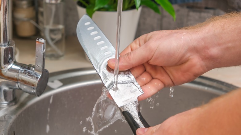 person rubbing fingers on stainless steel knife