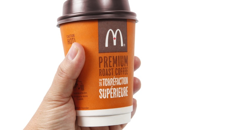 a hand holds a mcdonald's coffee cup
