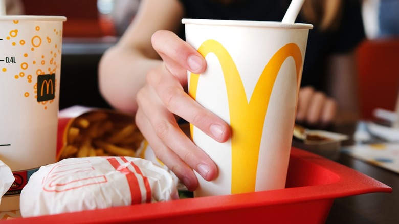 hand holds mcdonald's drink cup on tray