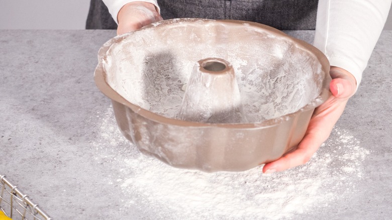 hands holding greased bundt pan