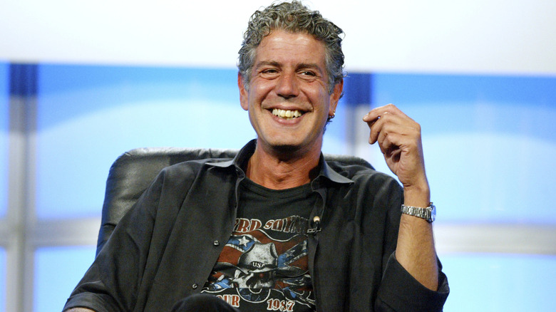 Anthony Bourdain sits on stage and smiles