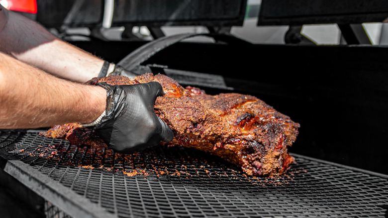Chef handling beef in a BBQ smoker