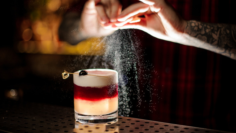 bartender squeezing citrus over a cocktail