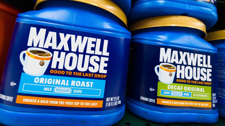 Closeup of Maxwell House coffee canisters on grocery shelf.