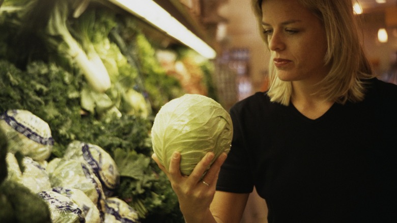 woman considers supermarket cabbage