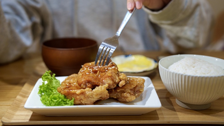 diner spears fried chicken with fork