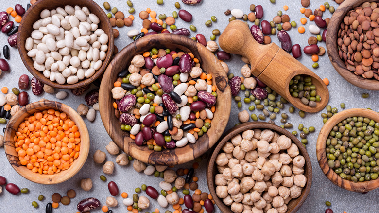 Top view of different beans, lentils, mung, chickpeas in wooden bowls